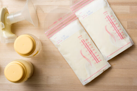 Frozen breast milk in bags next to bottles and a pump