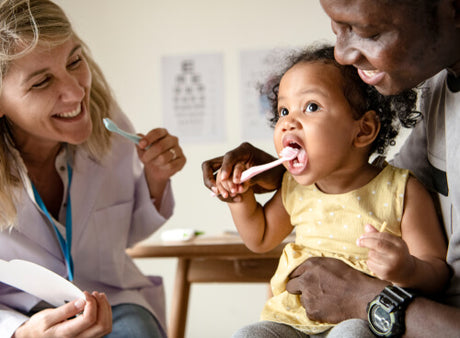 A dentist show's a father how to take care of his daugher's baby teeth.